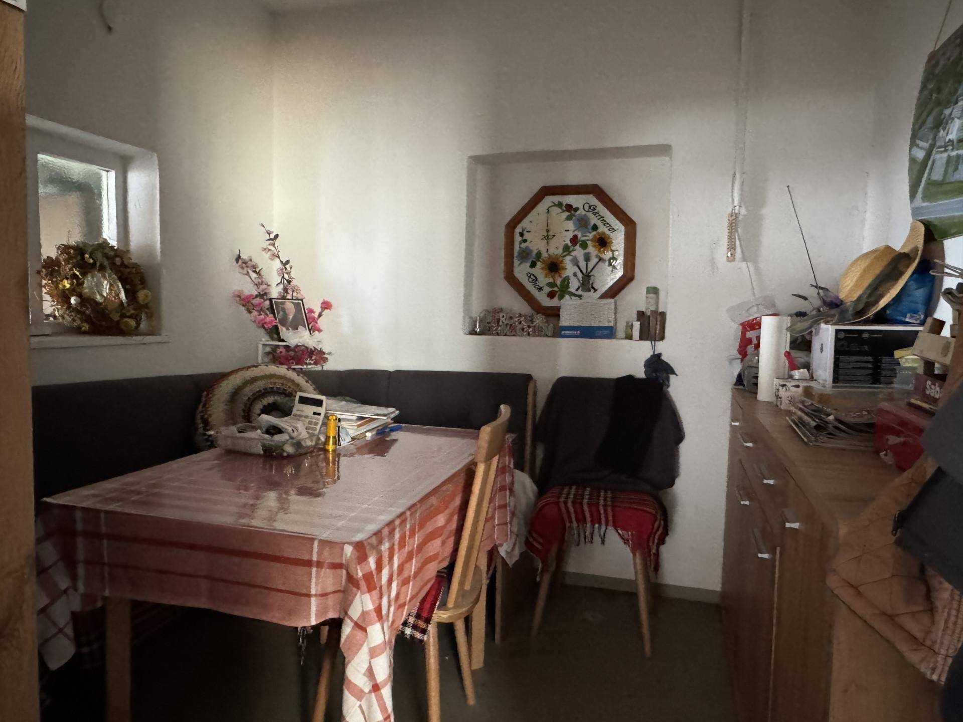 Kleiner Essbereich mit Bank, Tisch und traditioneller Dekoration an der Wand.