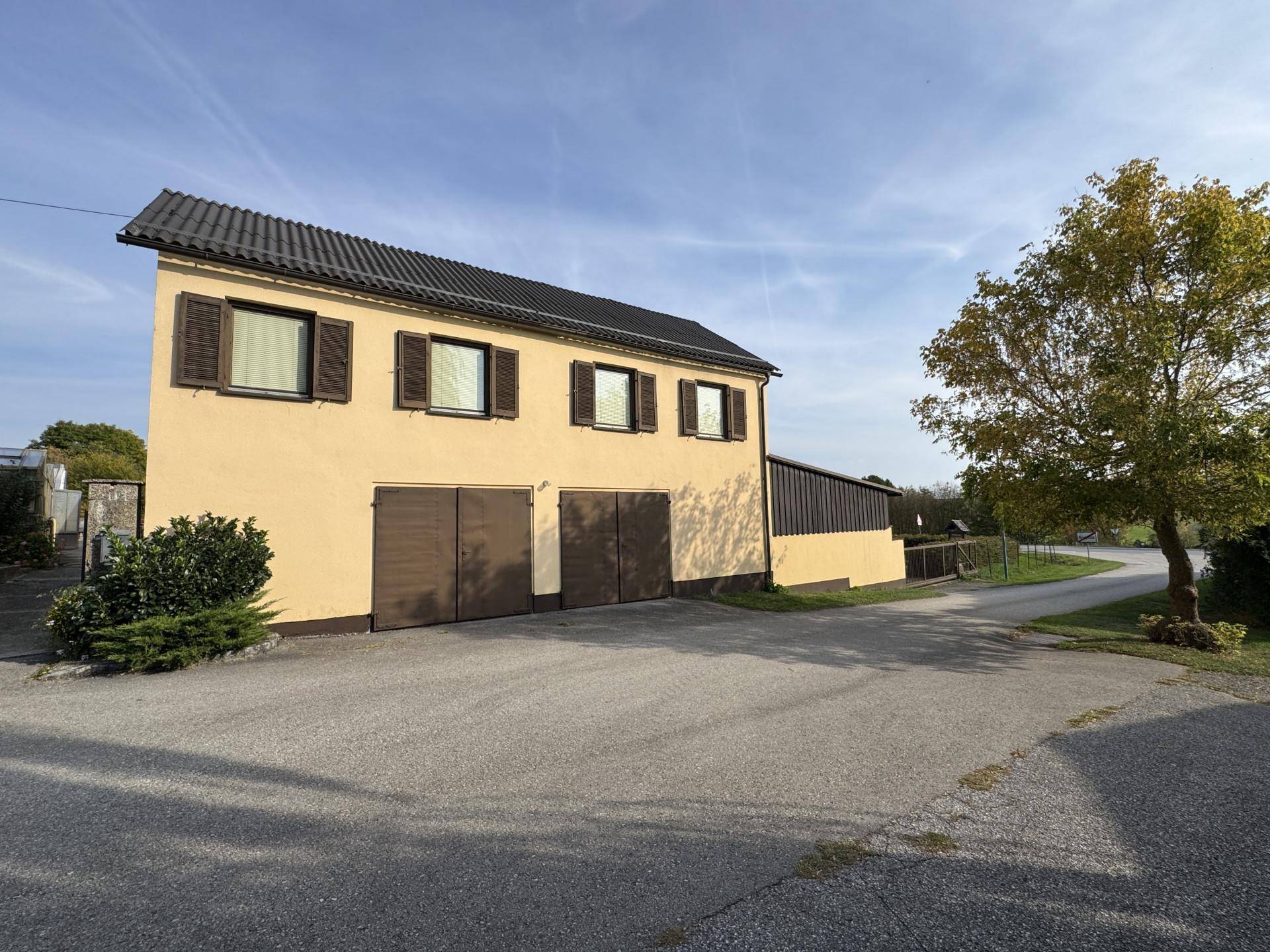 Gebäude mit zwei Garagen und einer breiten Zufahrt unter blauem Himmel.