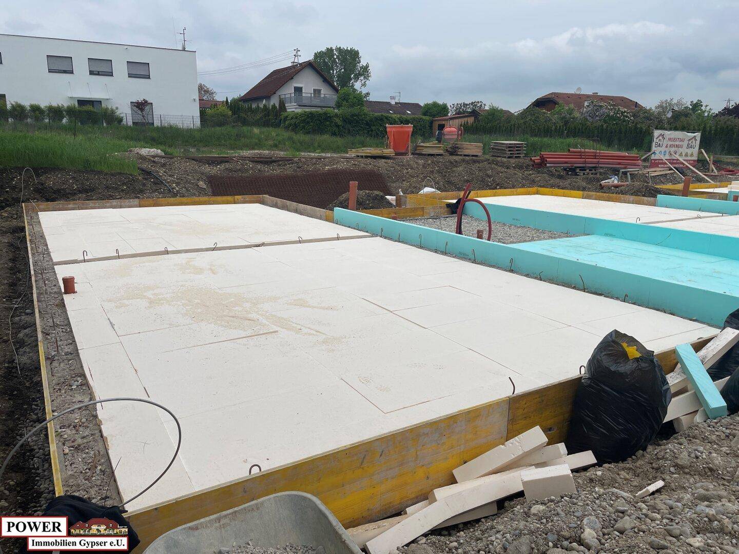 Baustelle mit vorbereitetem Fundament und Dämmplatten für ein neues Gebäude.