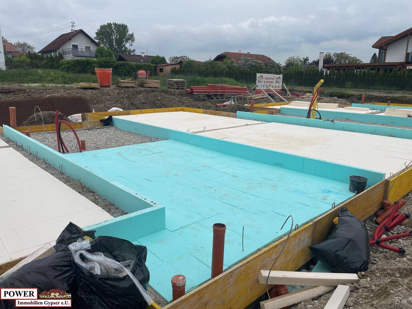 Fundamentarbeiten auf einer Baustelle mit blauen Dämmplatten und Rohren.
