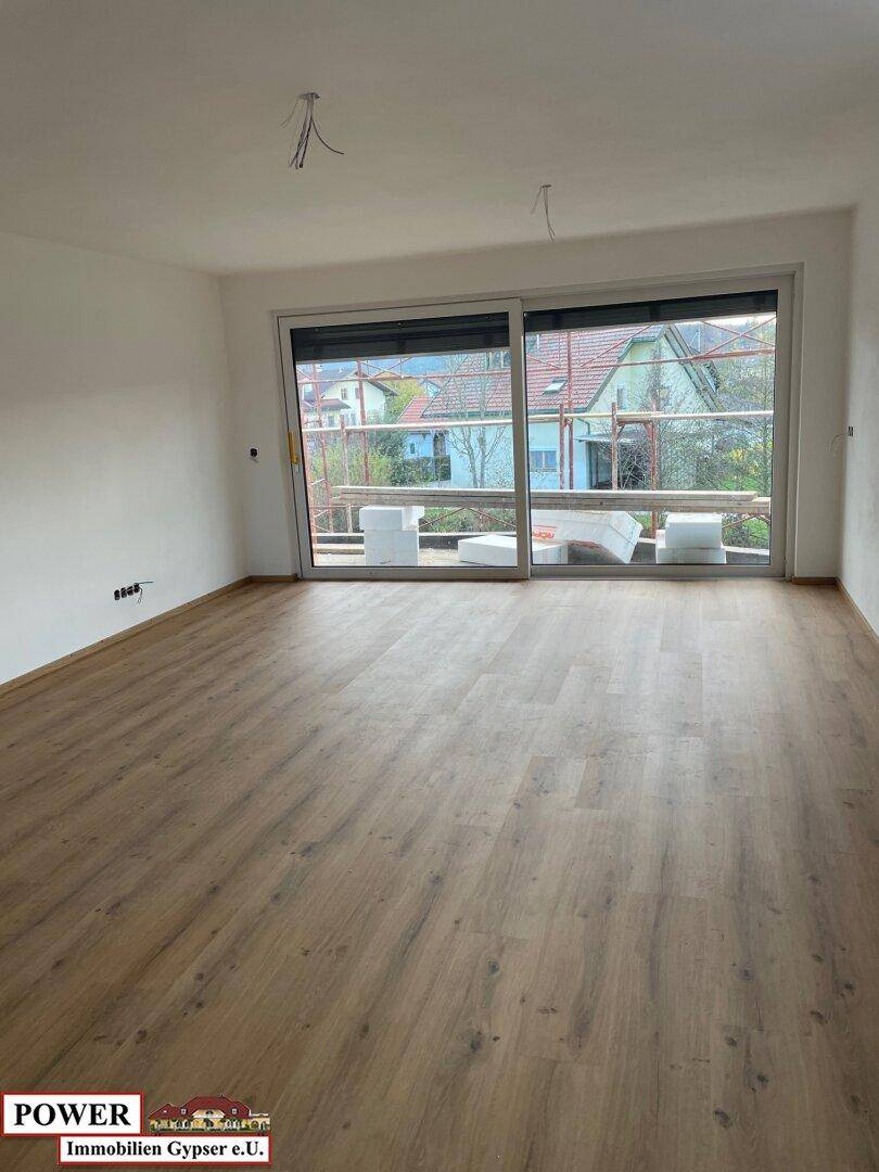Helles Wohnzimmer mit Laminatboden und großer Schiebetür, die viel Tageslicht hereinlässt.