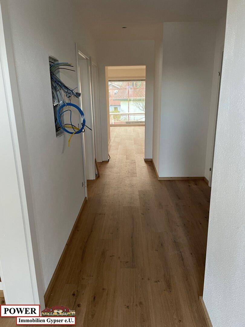 Heller Flur mit Laminatboden und Blick in einen weiteren Raum mit Fenster.