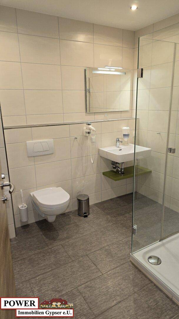 Modernes Badezimmer mit Duschkabine, wandhängendem WC und Waschbecken.