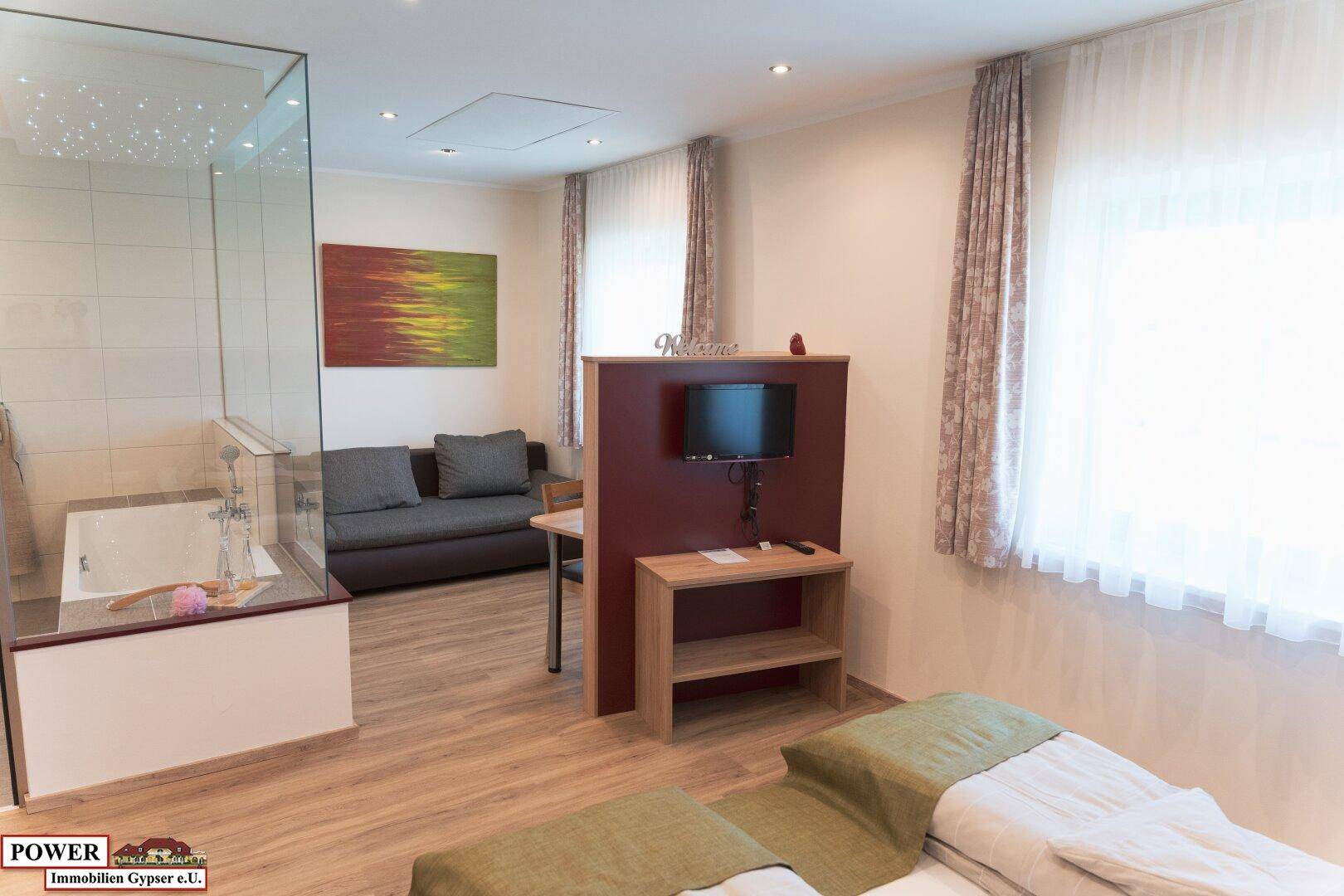 Geräumiges Schlafzimmer mit integrierter Badewanne, Sofa und Fernseher.