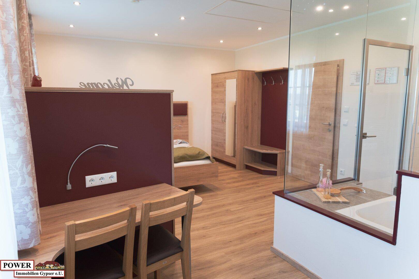 Modernes Schlafzimmer mit Holzboden, integrierter Badewanne und Schreibtischbereich.