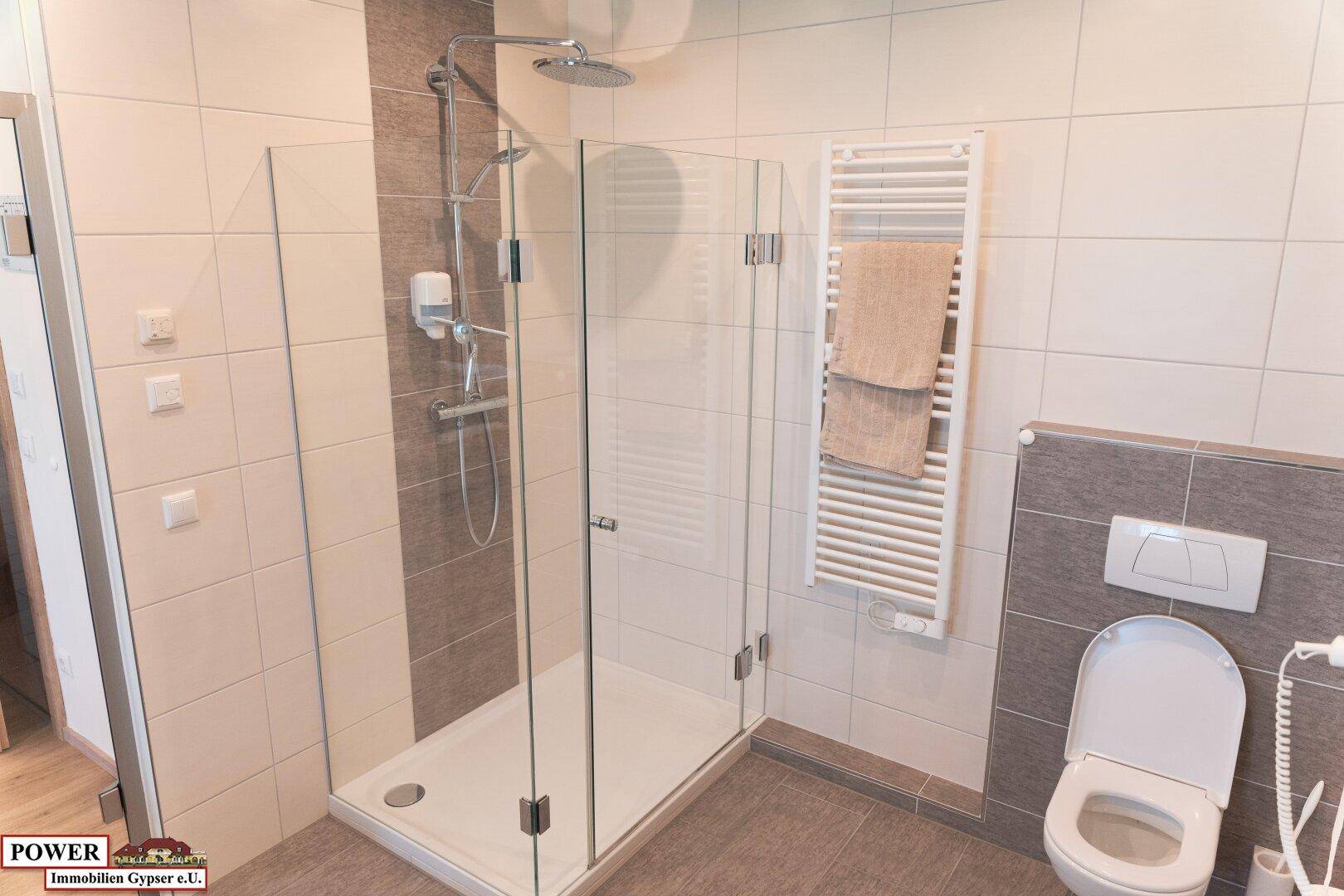 Modernes Badezimmer mit ebenerdiger Dusche, wandhängendem WC und Handtuchheizkörper.