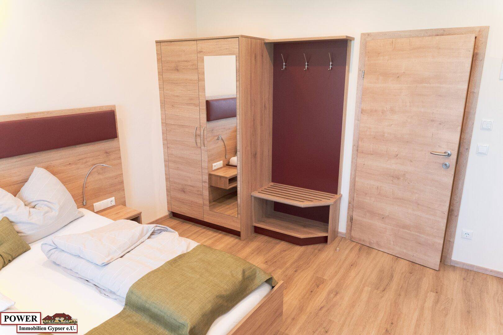 Schlafzimmer mit Holzbett, Kleiderschrank und Garderobenbereich.