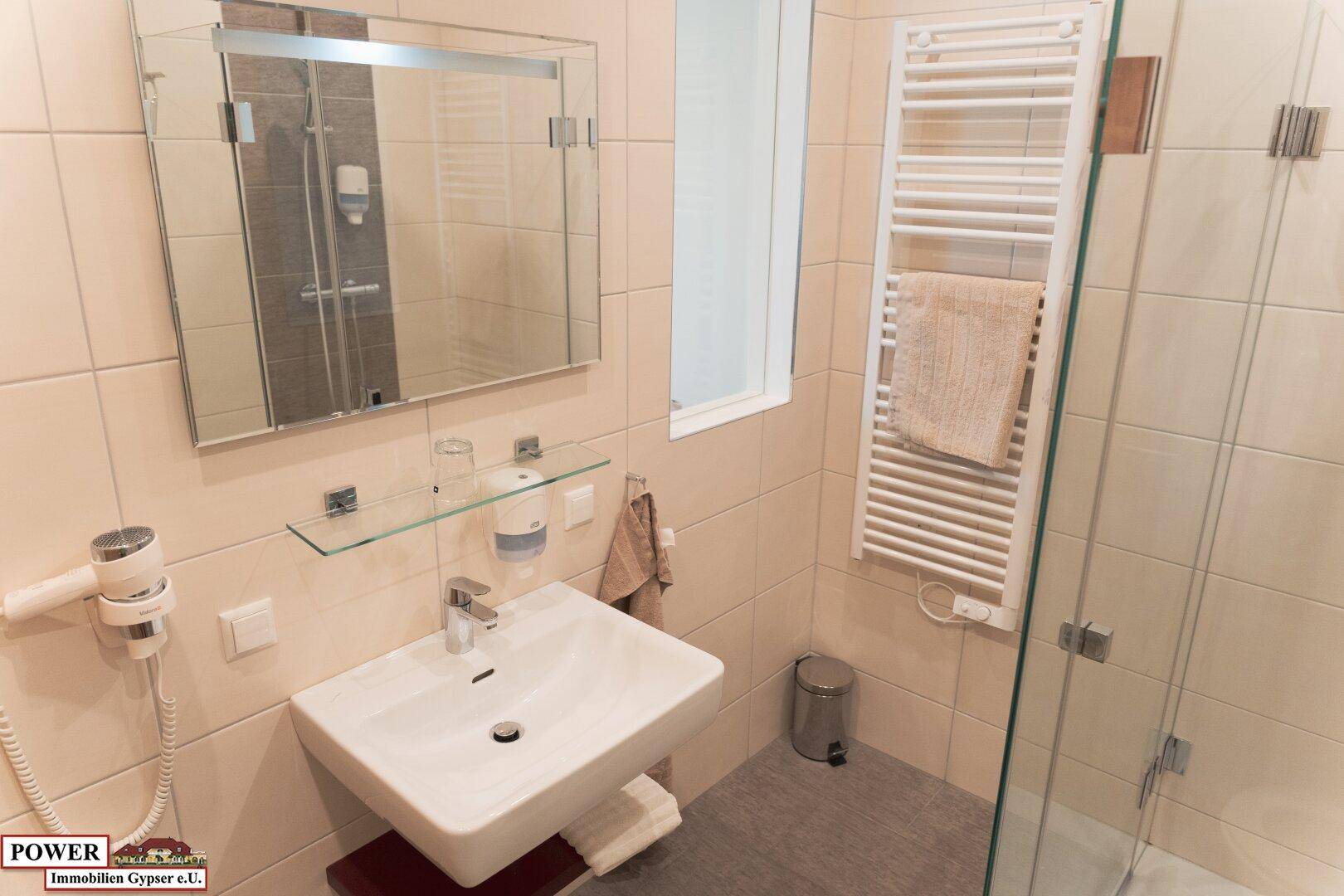 Modernes Badezimmer mit Waschbecken, Spiegel und Duschkabine.