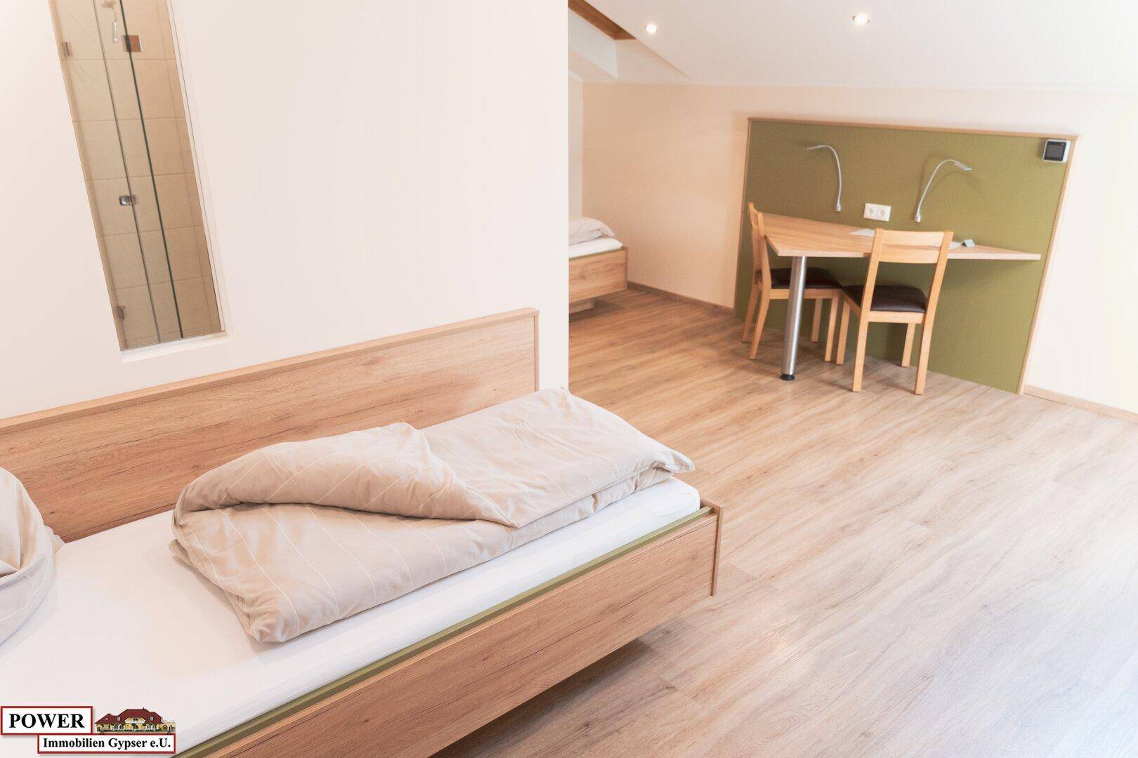 Schlafzimmer mit zwei Einzelbetten, Holzboden und Schreibtischbereich.