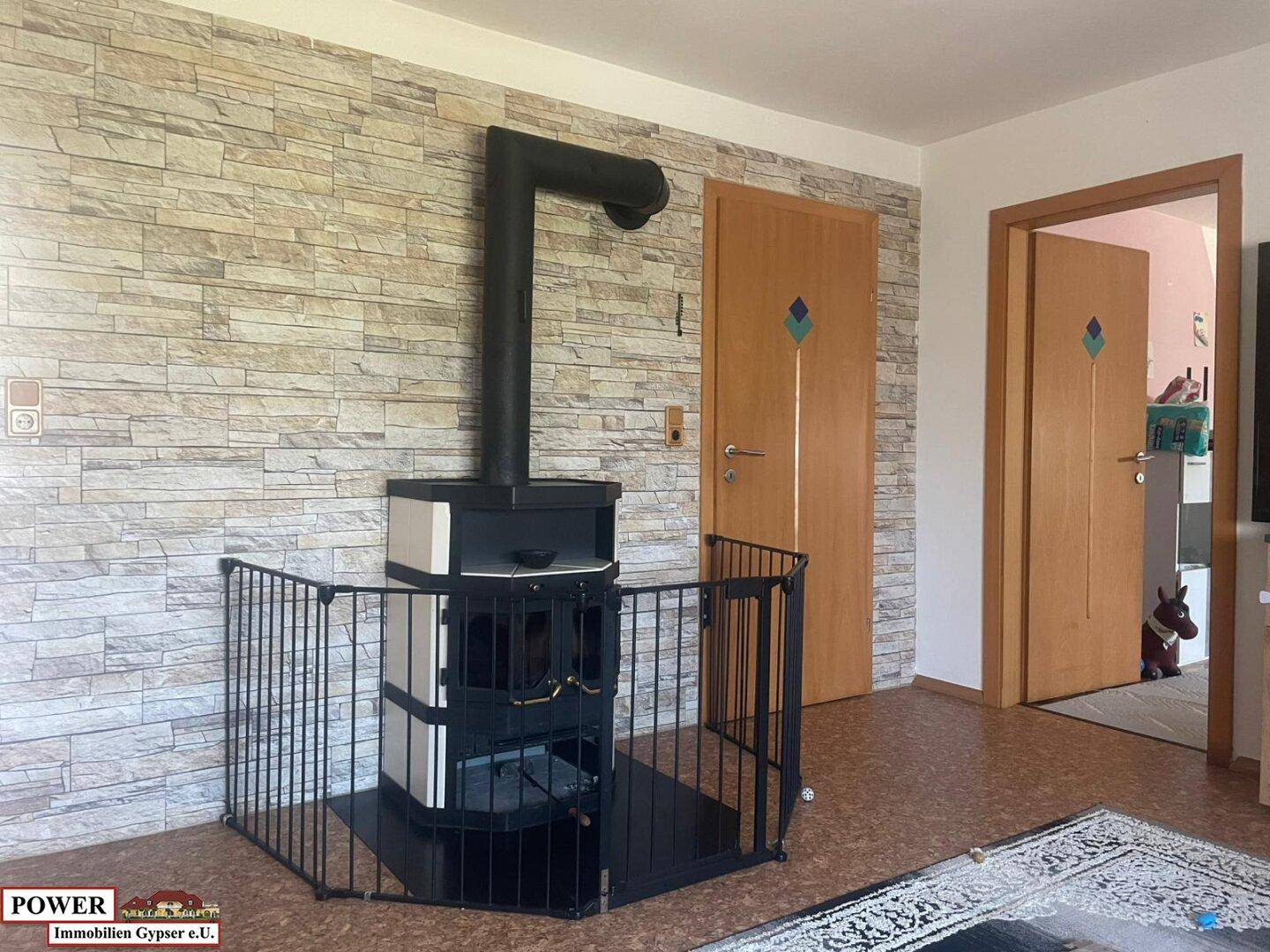 Gemütliches Wohnzimmer mit modernem Holzofen, Steinwandverkleidung und Holztüren.