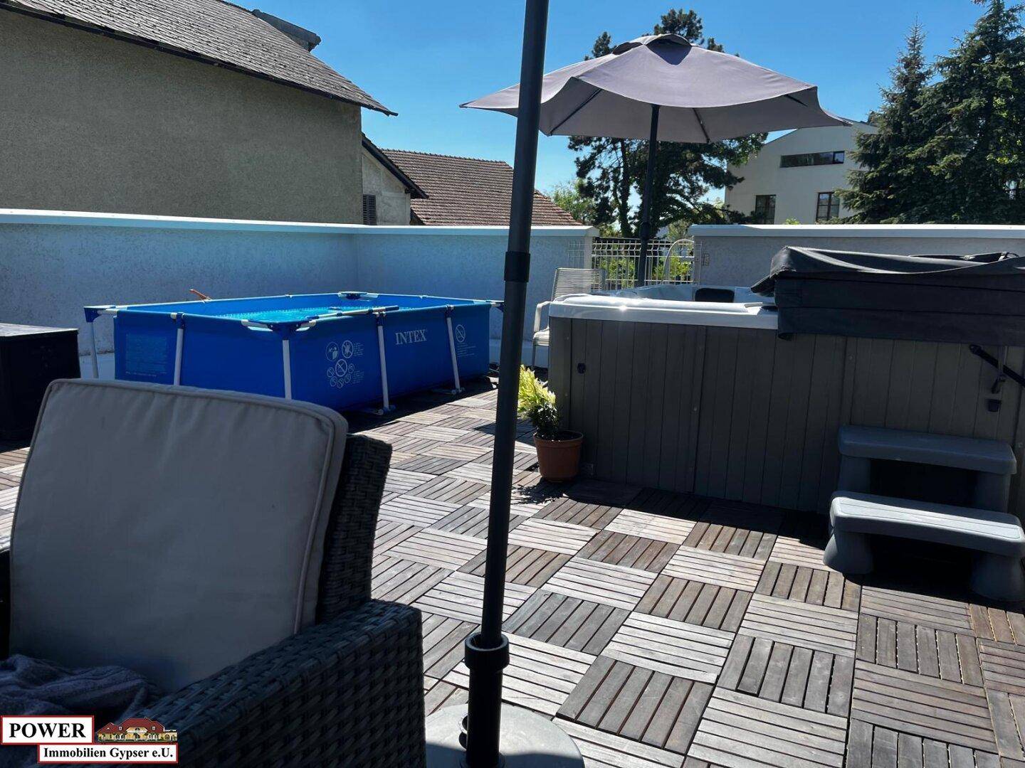 Große Dachterrasse mit Holzfliesen, Whirlpool, aufblasbarem Pool und Sonnenschirm für Entspannung.