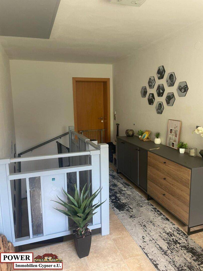 Eingangsbereich mit Treppe, moderner Kommode und dekorativer Wandgestaltung.