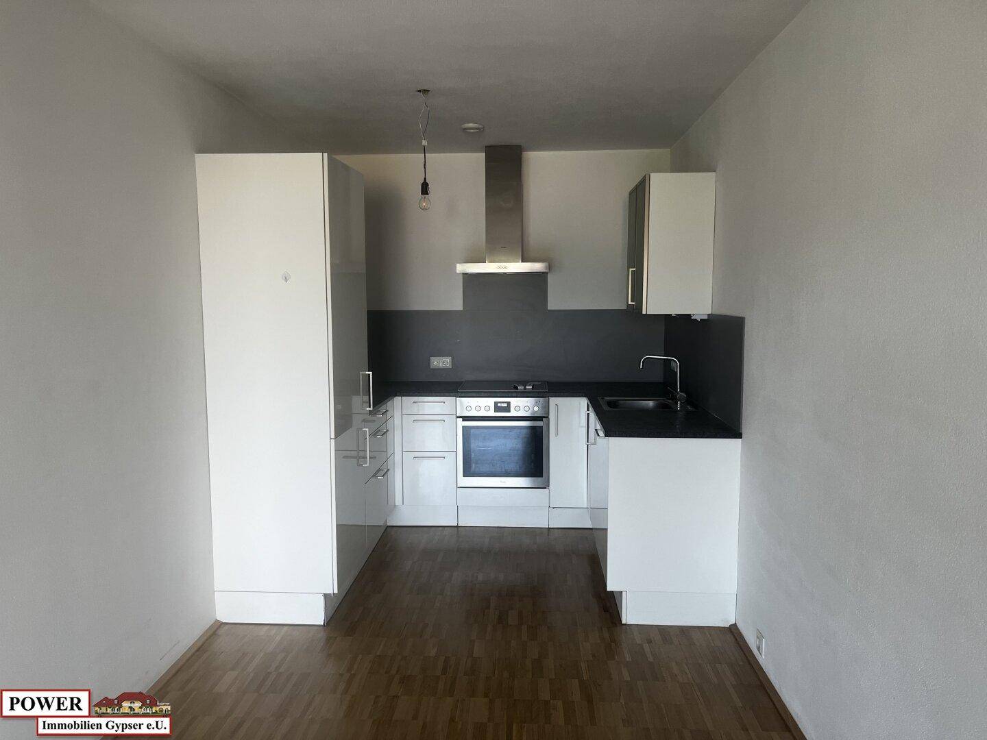 Kleine, moderne Küche mit weißen Schränken, schwarzer Arbeitsplatte und integrierten Geräten.