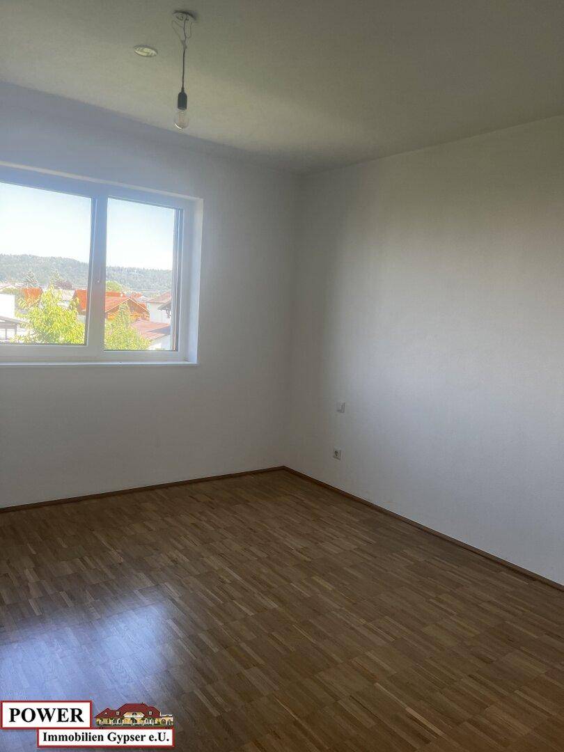 Helles Schlafzimmer mit Holzboden und einem Fenster, das einen weiten Ausblick bietet.