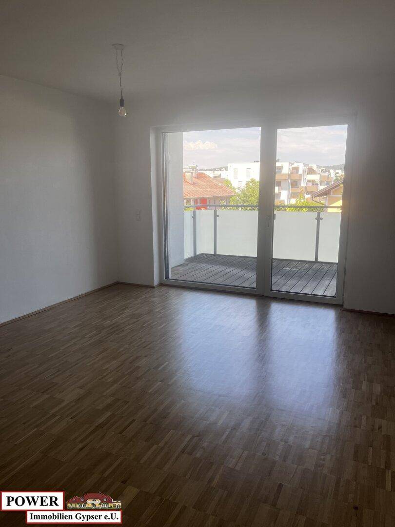 Geräumiges Zimmer mit Holzboden und großem Balkonzugang, ideal für natürliches Licht.