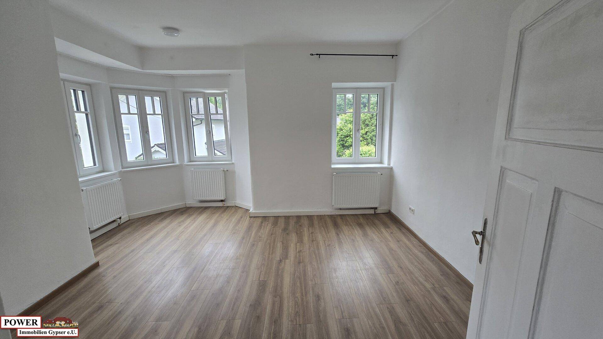 Heller Wohnraum mit Laminatboden und Erkerfenstern, bietet viel Tageslicht und einen angenehmen Ausblick.