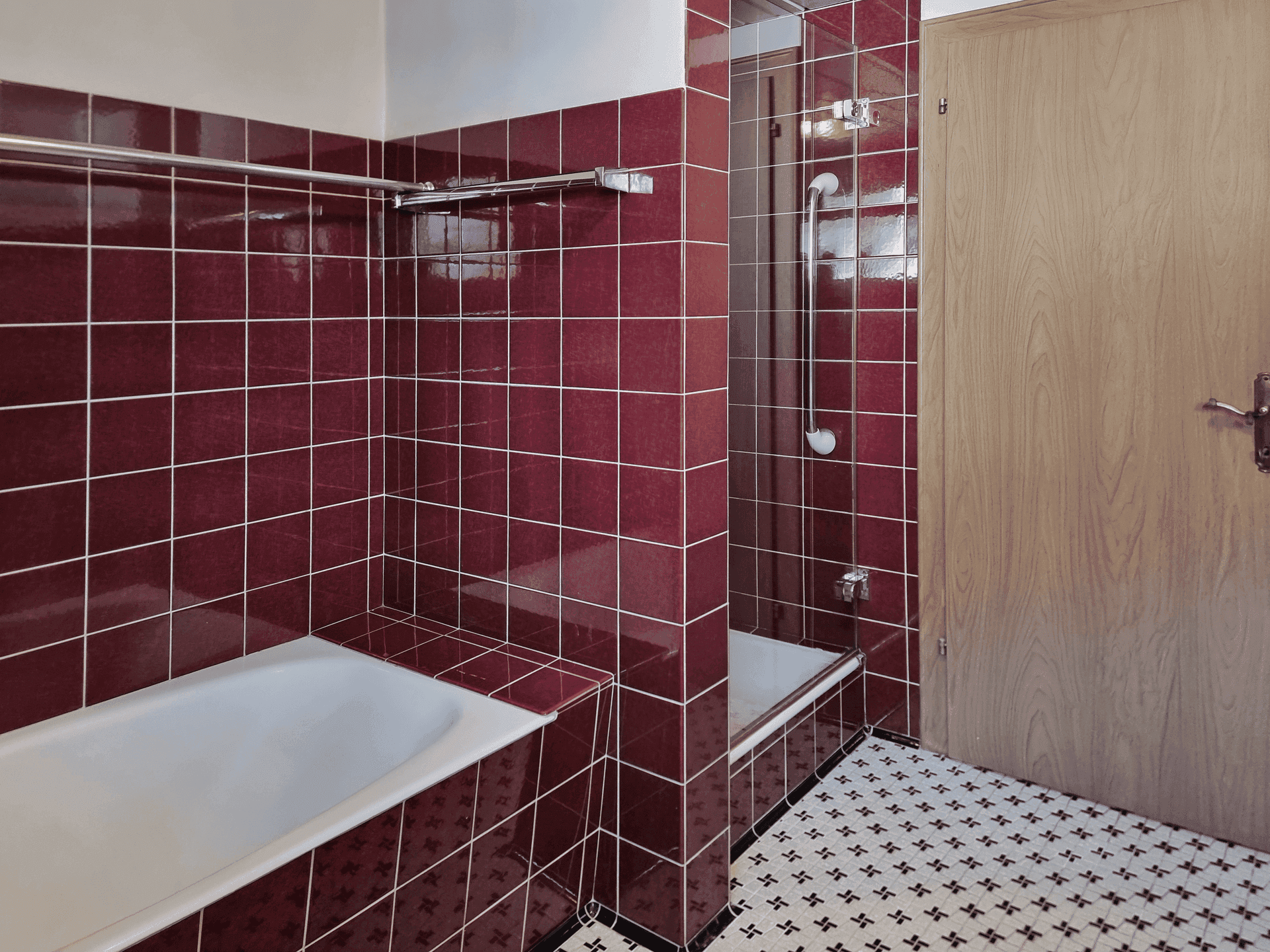 Badezimmer mit roten Fliesen, Badewanne und separater Dusche.