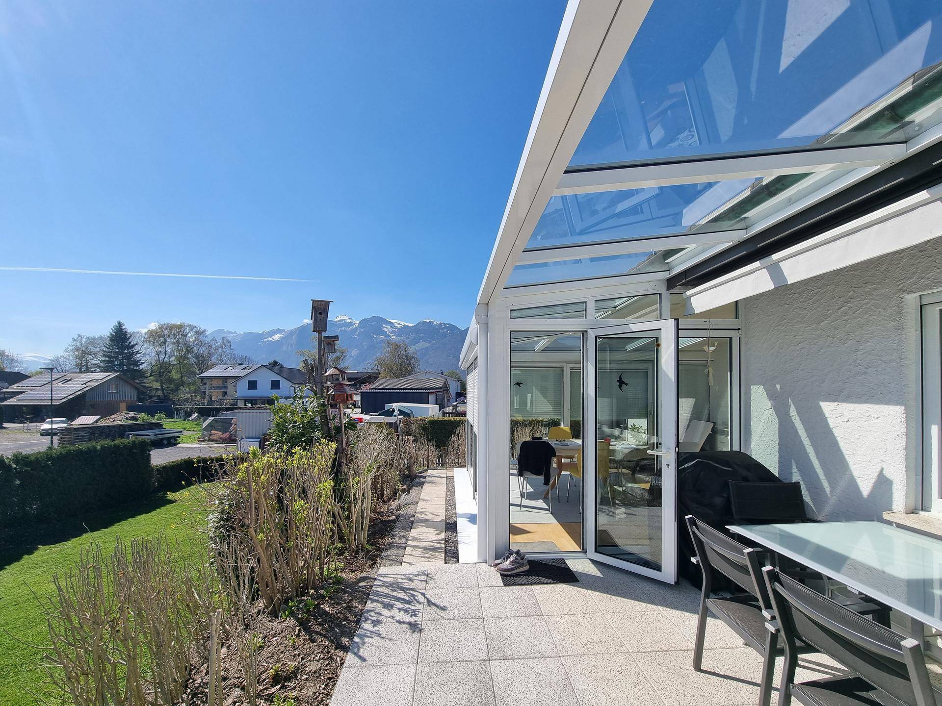 Überdachte Terrasse mit Bergblick, Gartenmöbeln und Zugang zum Wintergarten.