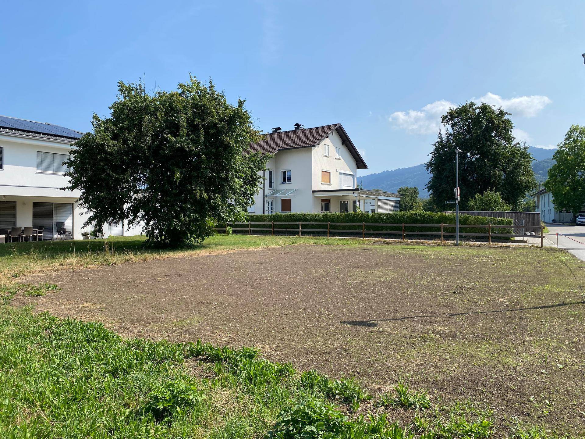 Weitläufiges Grundstück mit Blick auf ein traditionelles Wohnhaus und die umliegende Berglandschaft.