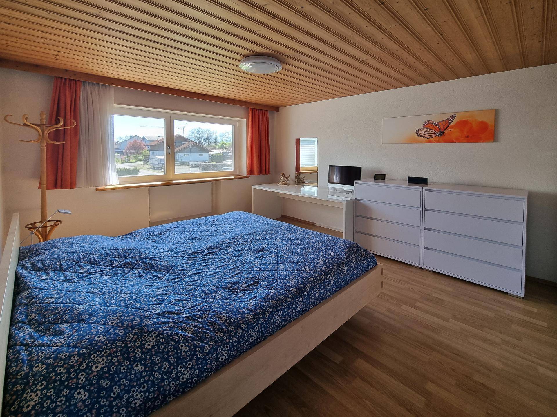 Geräumiges Schlafzimmer mit Schreibtisch, Kommode und Holzfußboden.