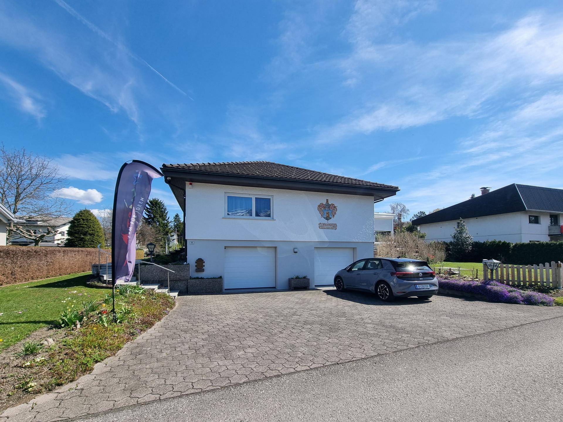 Vorderansicht des Hauses mit Doppelgarage, gepflasterter Einfahrt und Vorgarten.