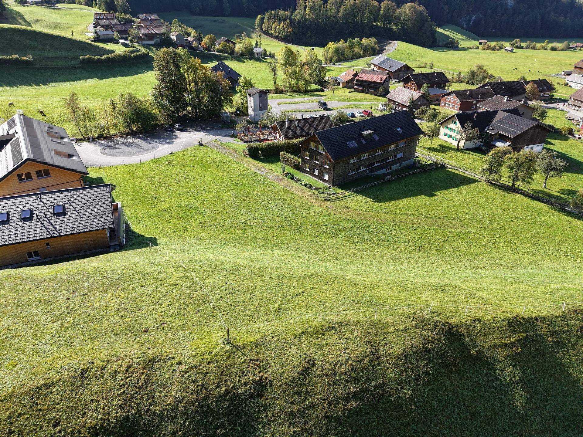 Weitläufiges grünes Grundstück aus der Vogelperspektive, umgeben von Wohnhäusern und einer Straße.