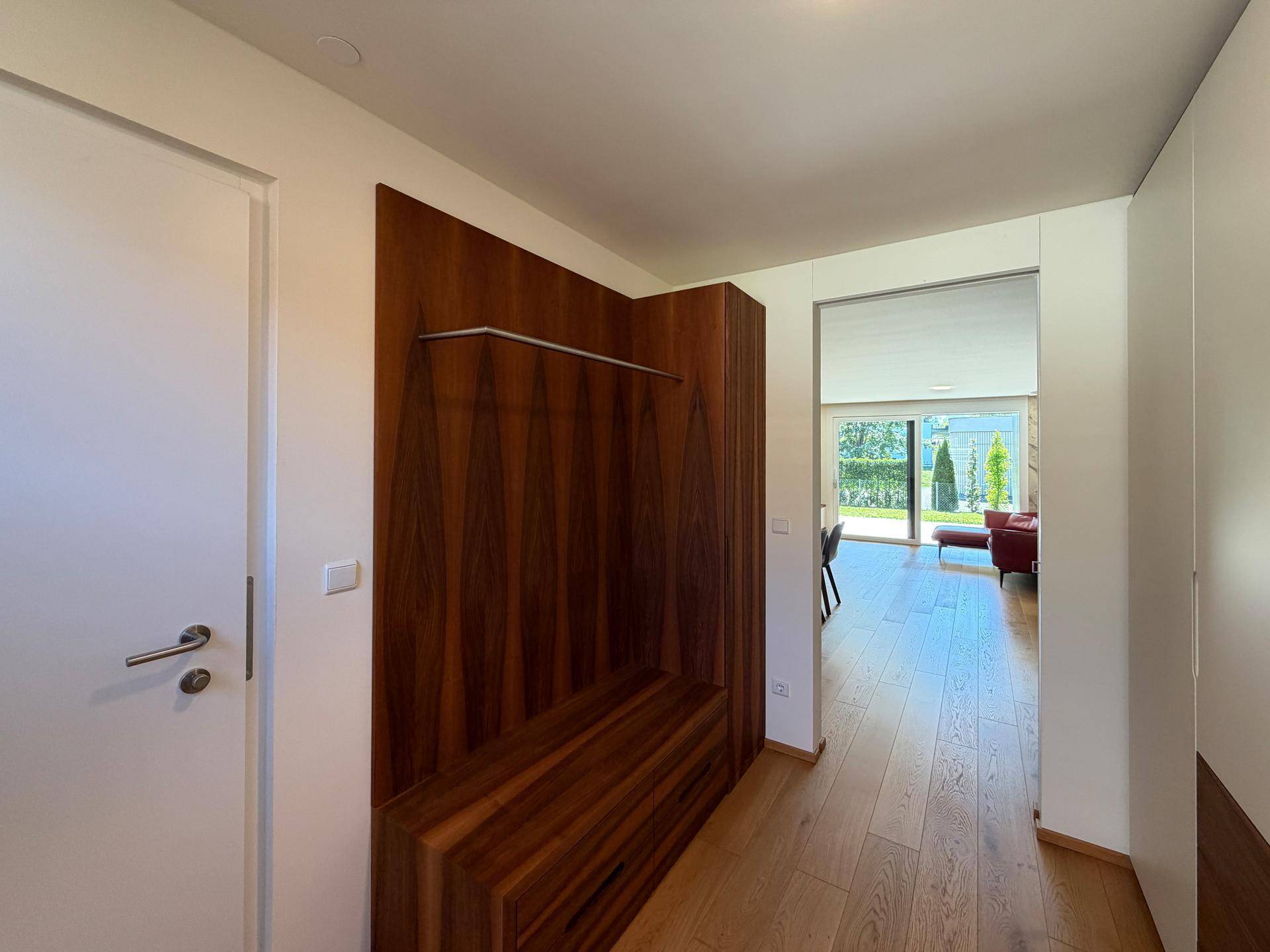 Moderner Flur mit integrierter Garderobe und Sitzbank, Blick in den Wohnbereich.