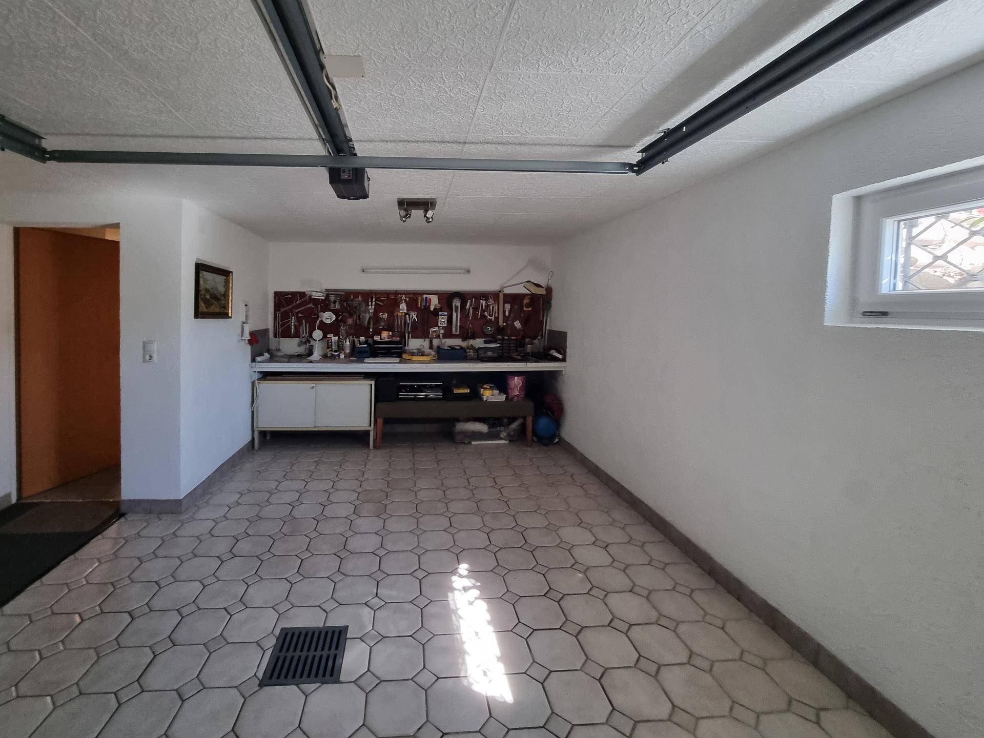 Garage mit Werkbank, Fliesenboden und Fenster, ideal für Heimwerker.