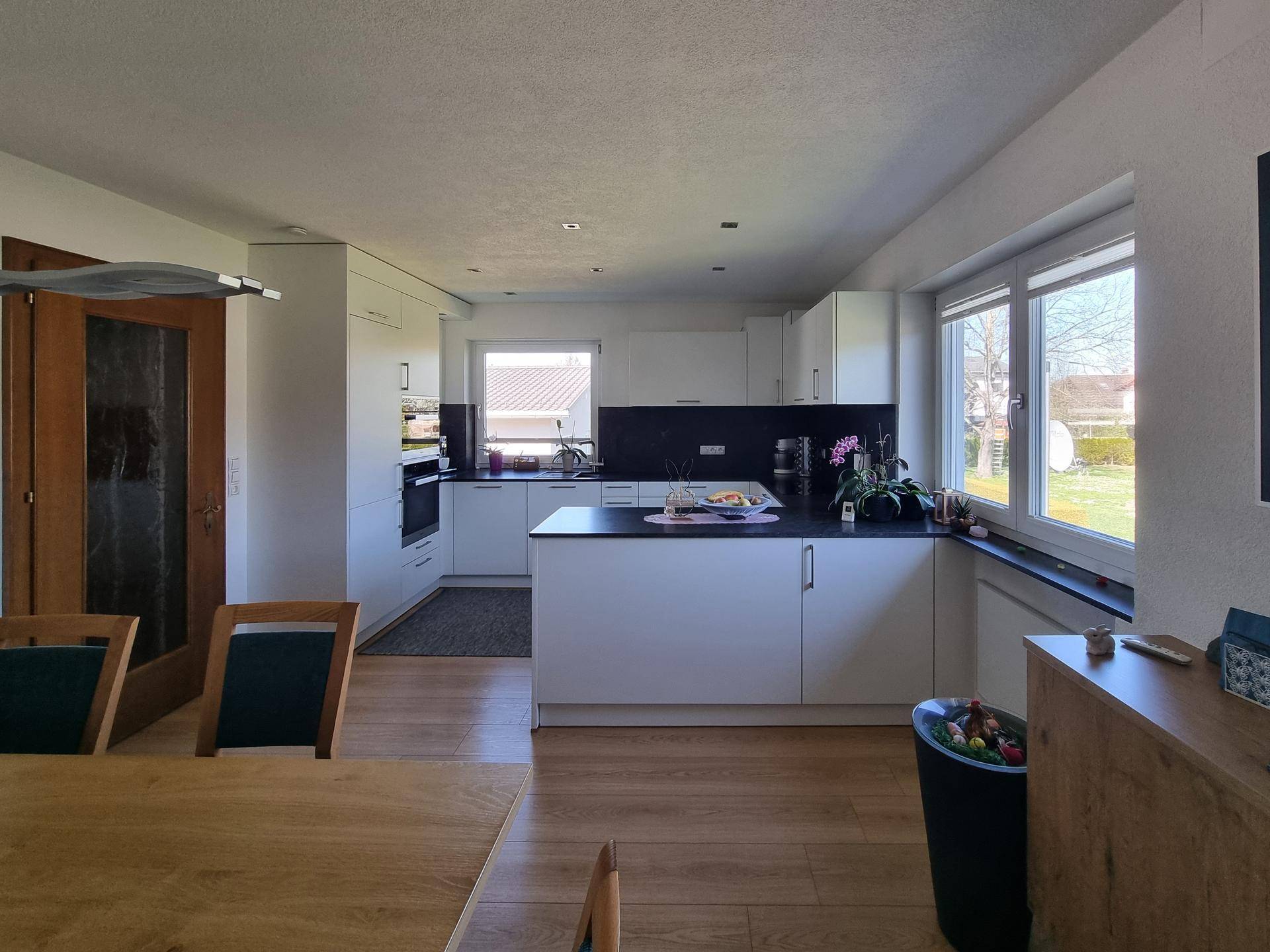 Offene Küche mit Essbereich, modernen Geräten und Blick in den Garten.