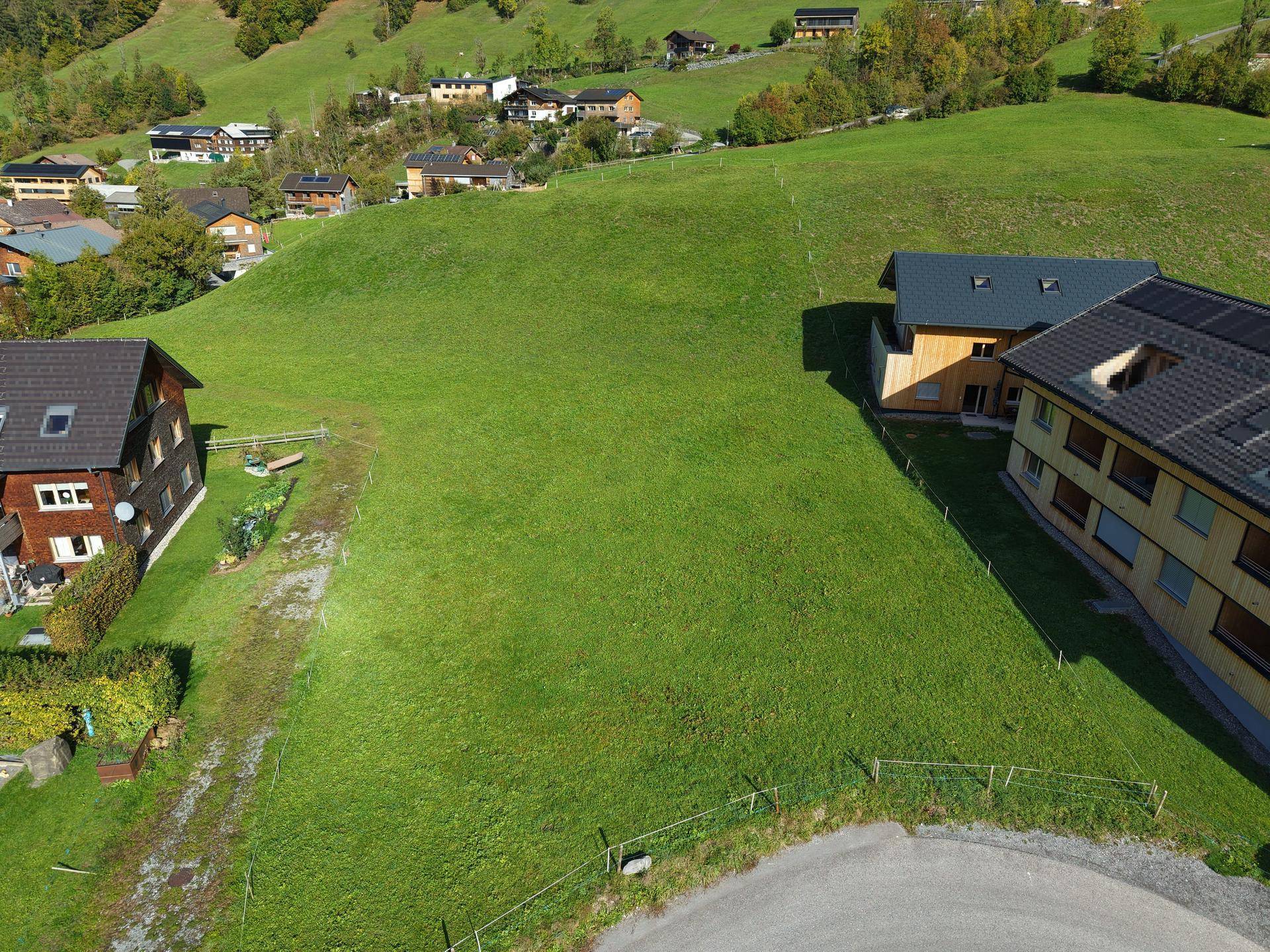 Luftaufnahme eines großen, grünen Grundstücks mit angrenzenden Häusern in ländlicher Umgebung.