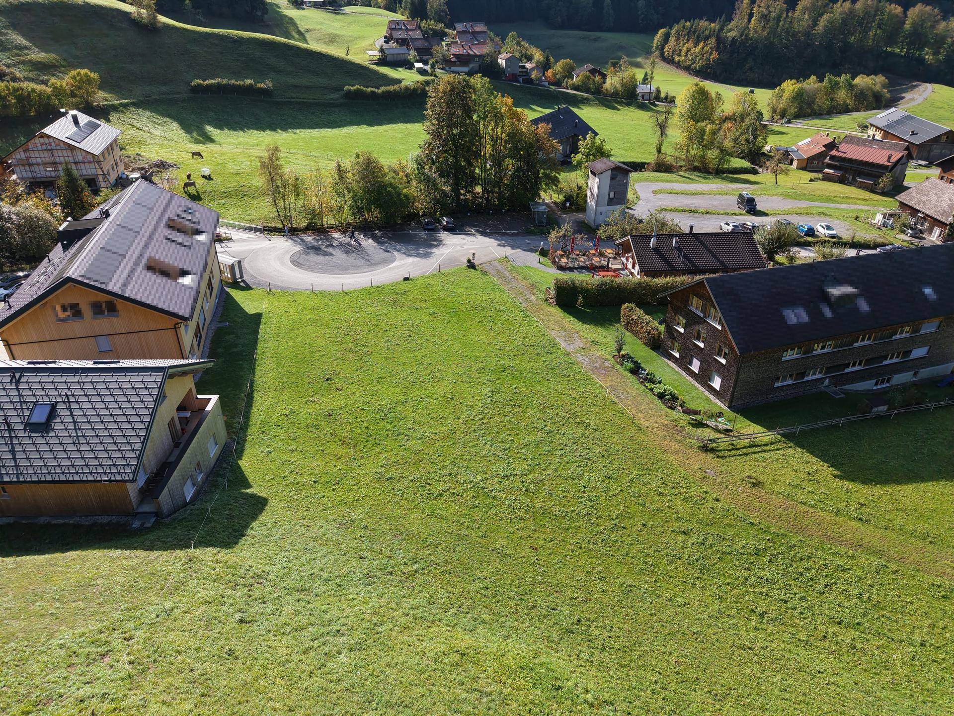 Großes, unbebautes Grundstück mit grüner Wiese, umgeben von Häusern und einer Straße.