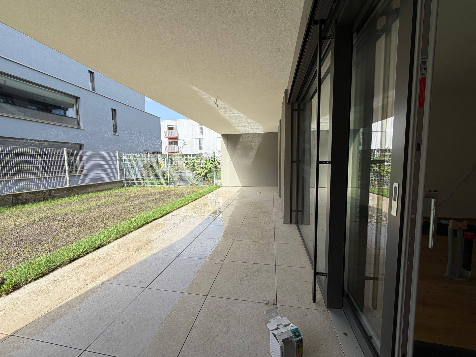 Lange, geflieste Terrasse im Erdgeschoss mit Zugang zum Gartenbereich und großen Schiebetüren.