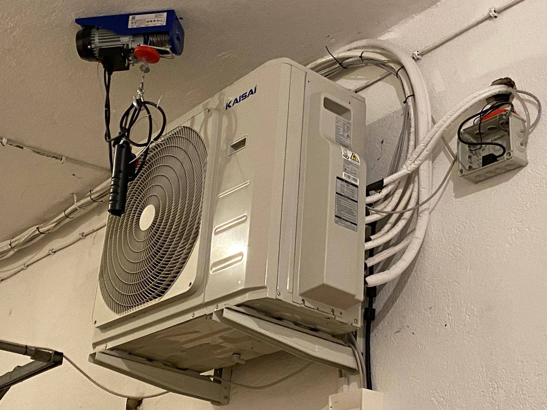 Klimaanlage an der Wand montiert mit sichtbaren Leitungen und Verkabelung in einem Technikraum.