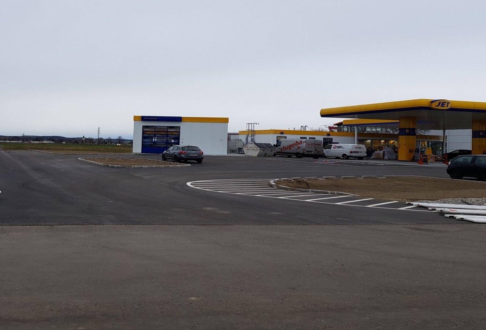 Eine JET-Tankstelle mit angeschlossener Autowaschanlage und Parkplätzen unter bewölktem Himmel und Zufahrten.
