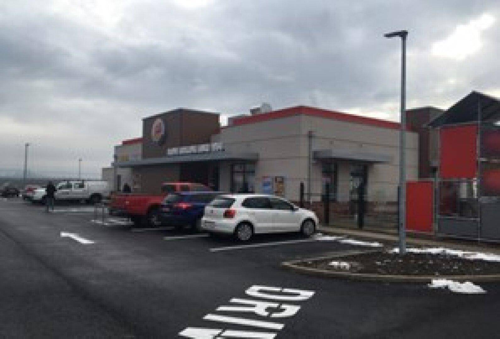 Parkplatz und Drive-Thru-Bereich eines Burger King Restaurants unter einem bewölkten Winterhimmel mit Schnee.