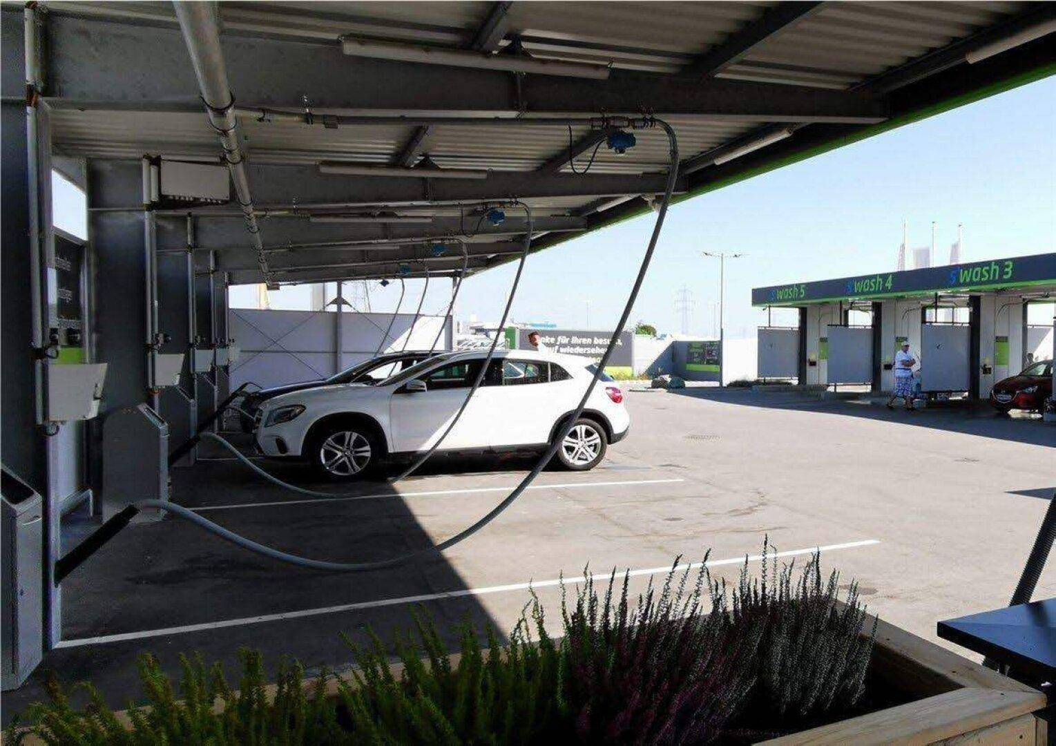 Überdachte Staubsaugerplätze der Autowaschanlage an einem sonnigen Tag mit einem geparkten Auto.