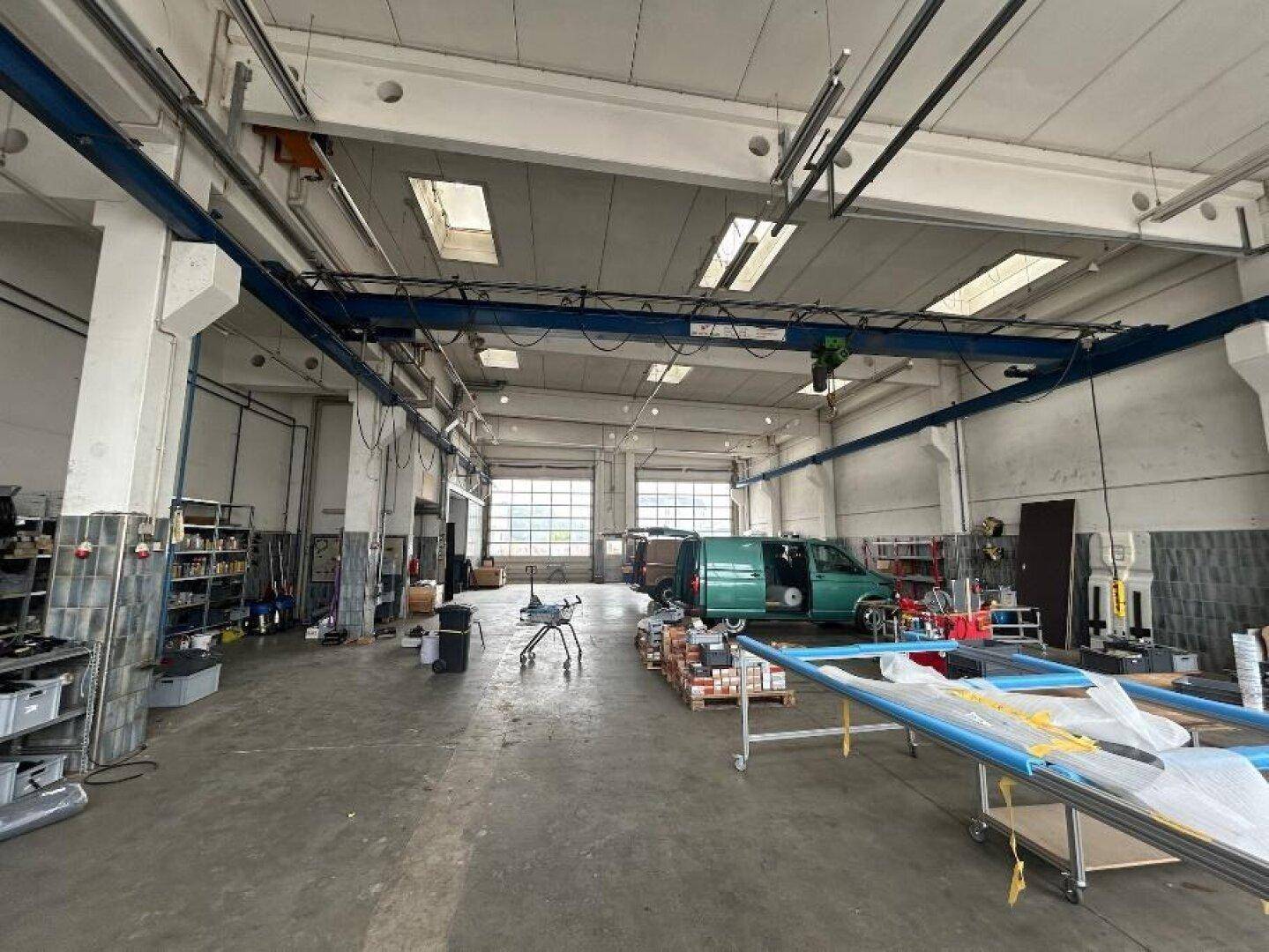 Große Lagerhalle oder Werkstatt mit hohen Decken, Betonboden und einem Kranbahnsystem.