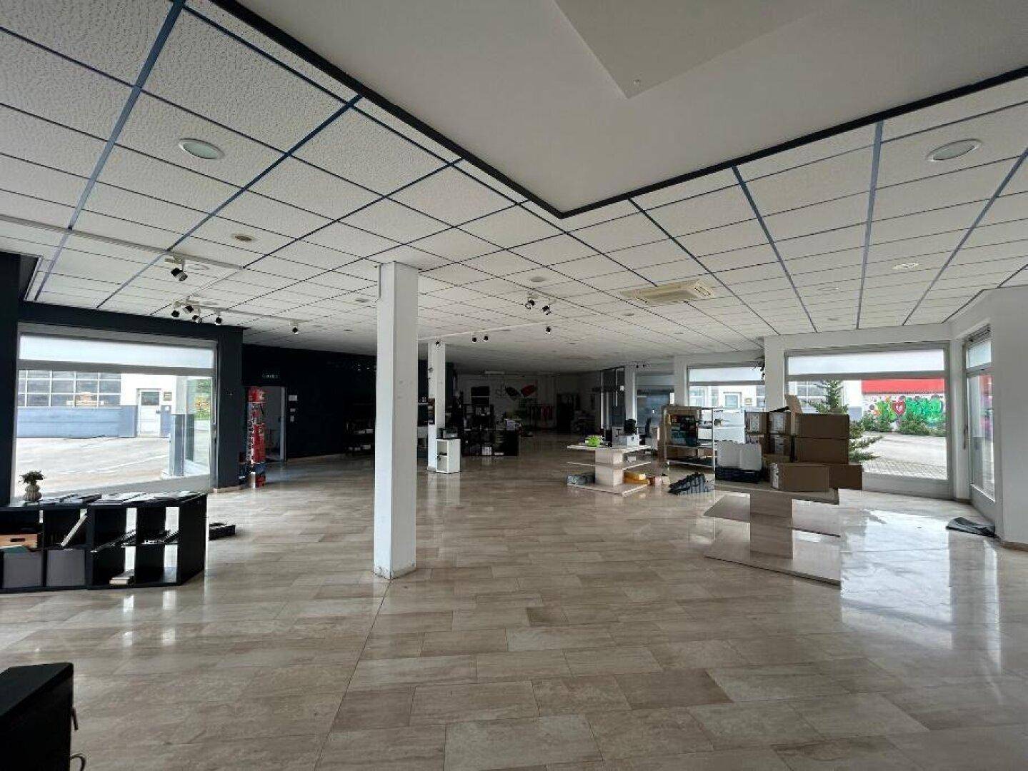 Großer, offener Verkaufsraum mit hellen Fliesenböden, abgehängter Decke und großen Schaufenstern.