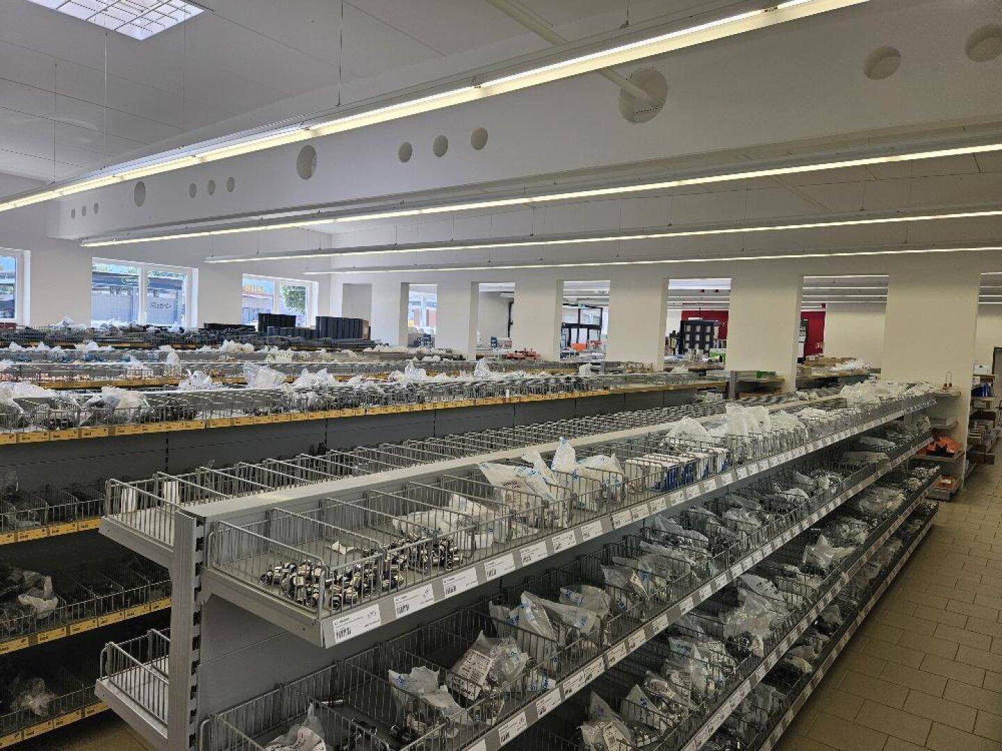 Langer Gang in einem Verkaufsraum mit Regalen voller Installationsmaterialien und Produkten.