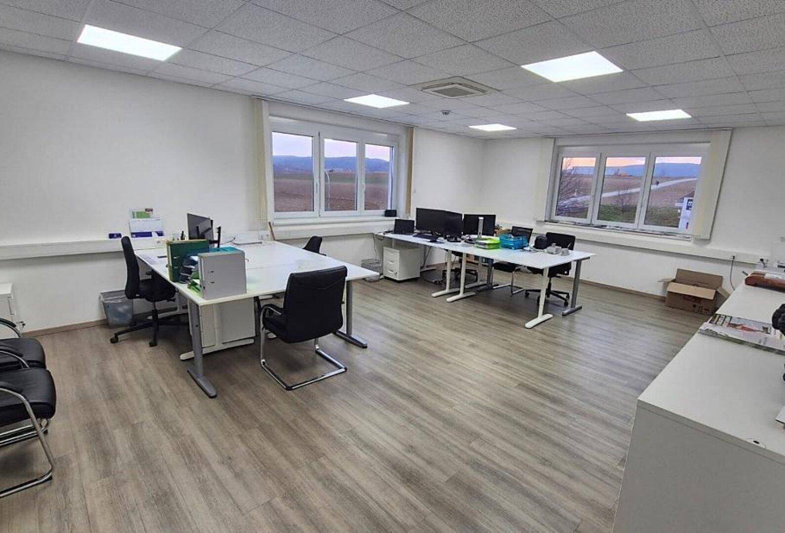 Helles und geräumiges Büro mit mehreren Arbeitsplätzen, großen Fenstern und Blick ins Grüne.
