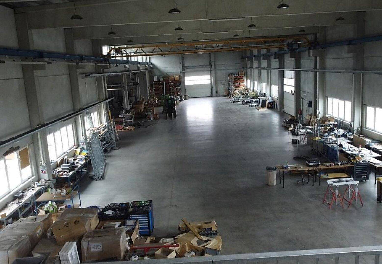Geräumige Lagerhalle mit hoher Decke, Betonboden und industrieller Ausstattung für vielfältige Nutzung.