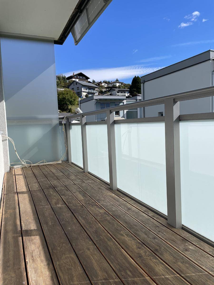 Geräumiger Balkon mit Holzboden und Blick auf die umliegende Wohngegend.