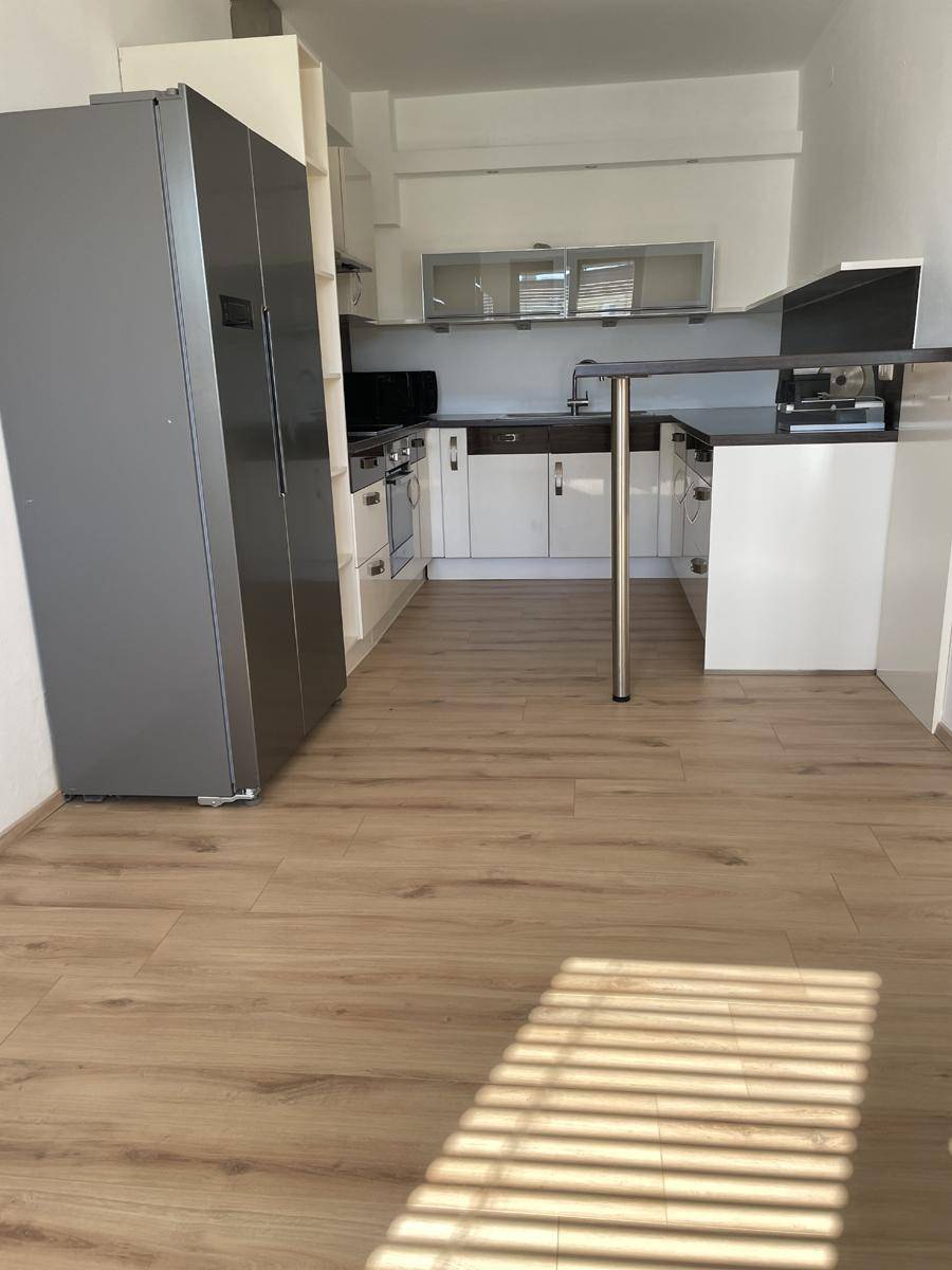 Moderne Küche mit Laminatboden, Einbaugeräten und integrierter Frühstücksbar.