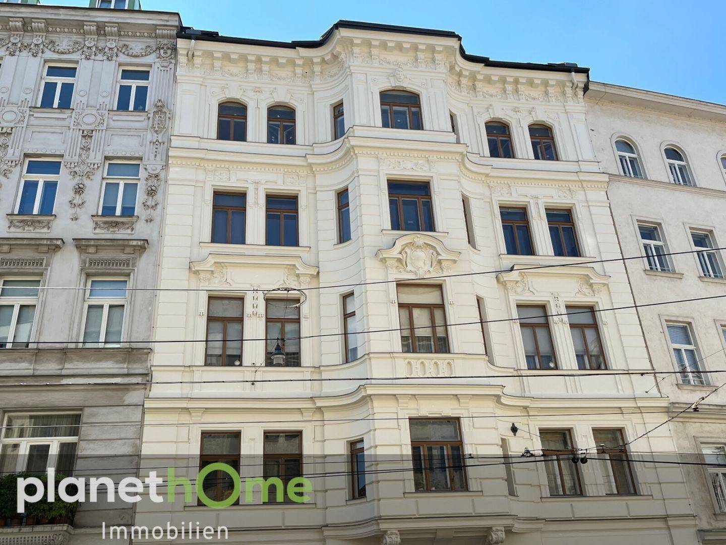 Historische Fassade eines Altbaus mit eleganten Verzierungen und vielen Fenstern.