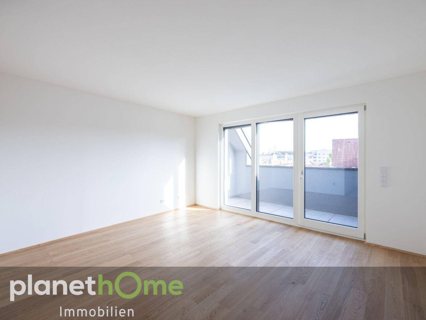 Heller Raum mit Holzboden und großer Schiebetür zum Balkon oder zur Terrasse.