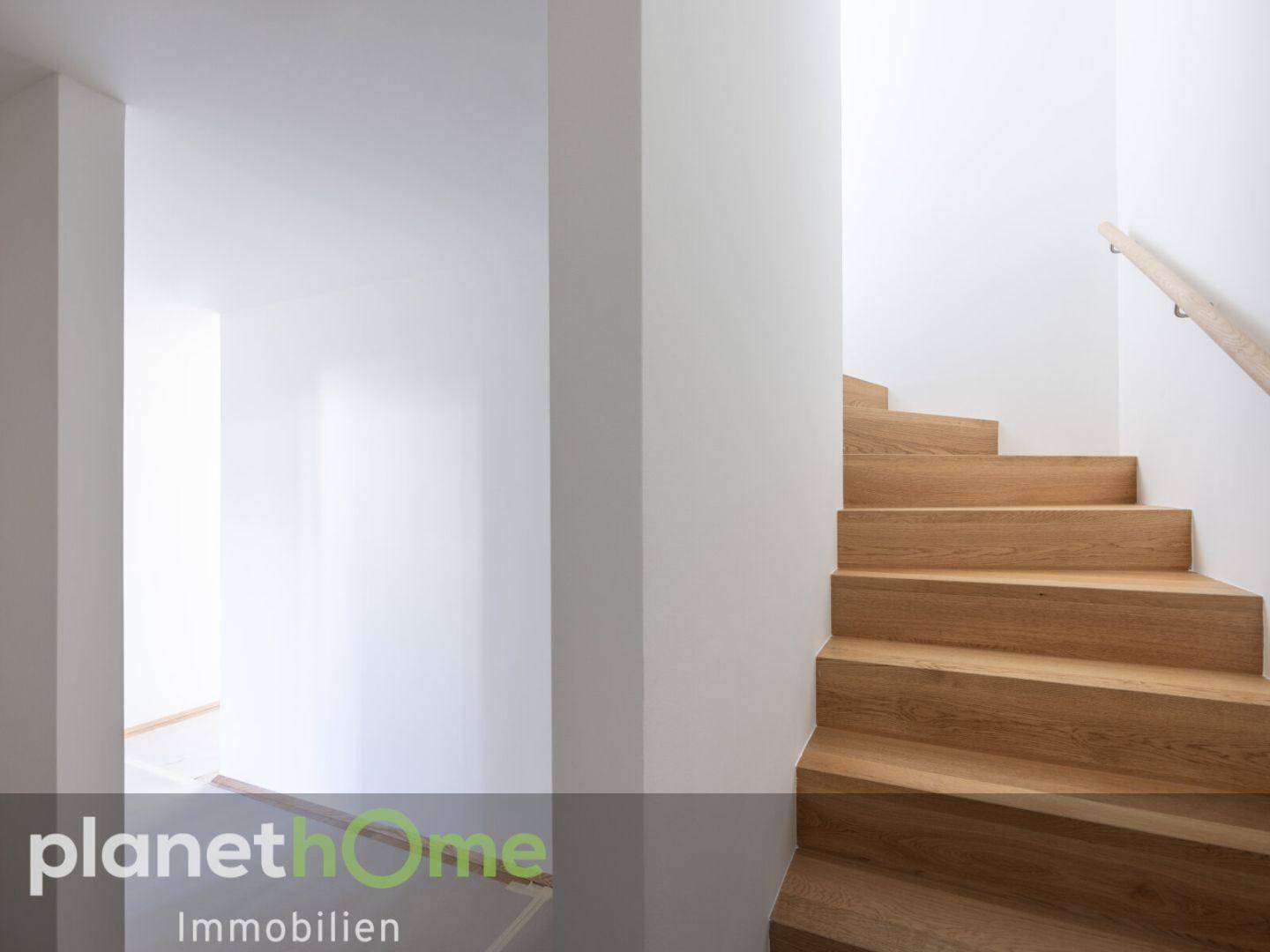 Elegante Holztreppe mit hellem Geländer, die verschiedene Ebenen des Hauses verbindet.