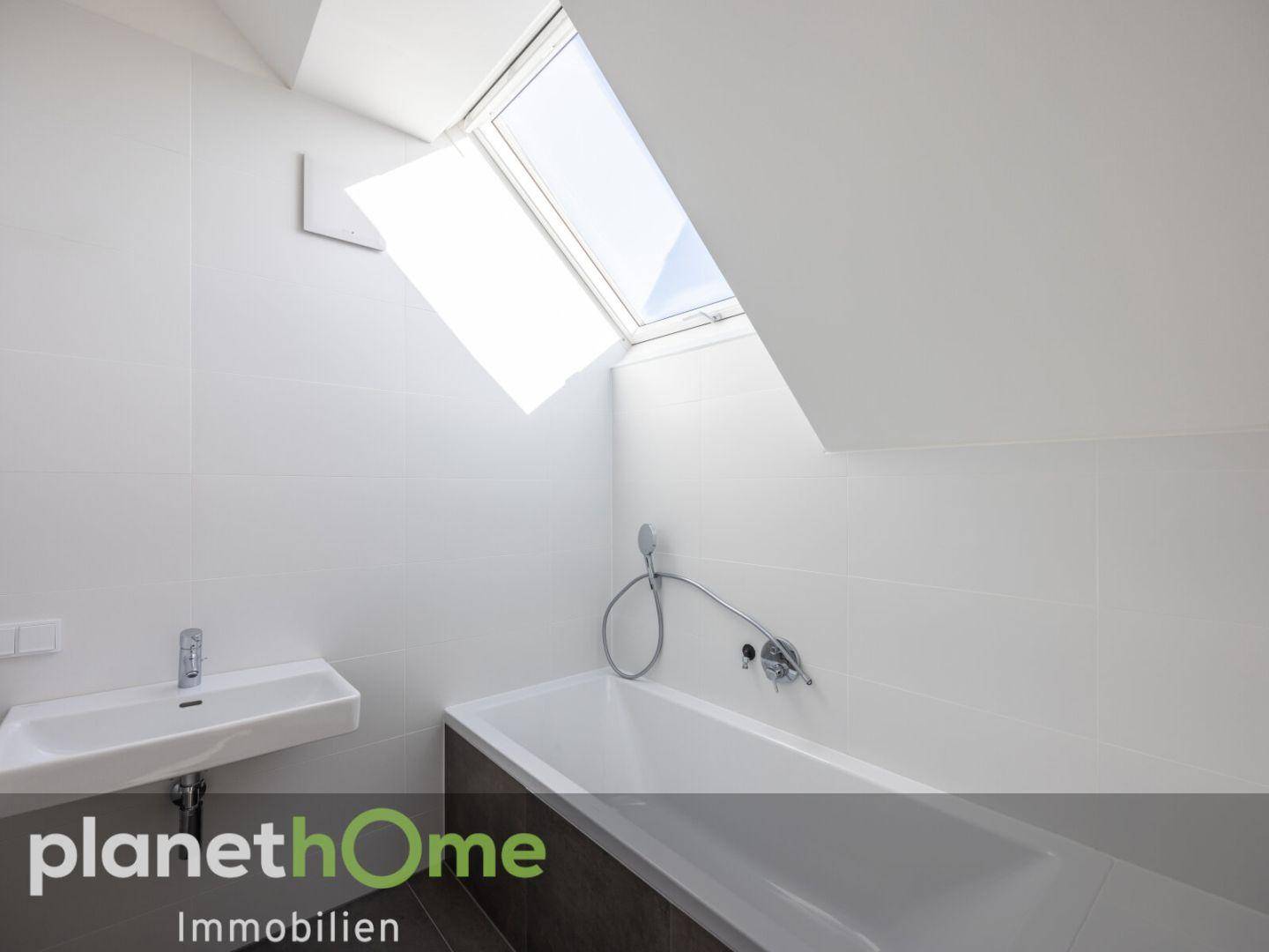 Badezimmer mit Badewanne, Waschbecken und Dachfenster für natürliches Tageslicht.