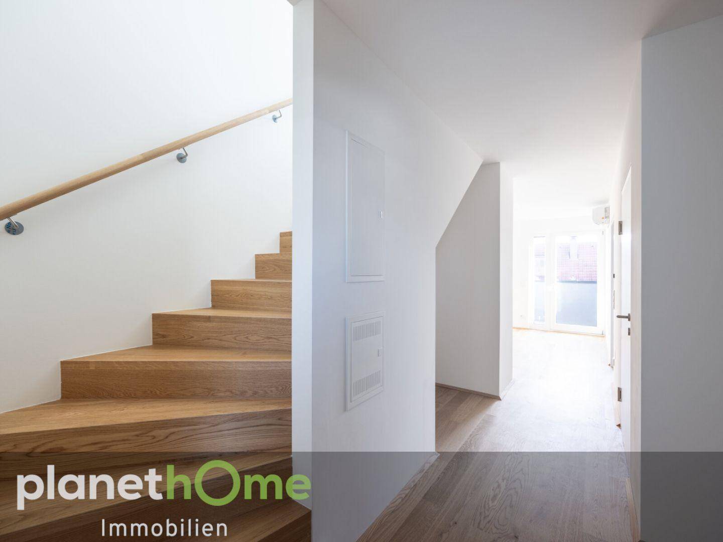Heller Flur mit Holztreppe und passendem Holzboden, der zu den oberen Etagen führt.