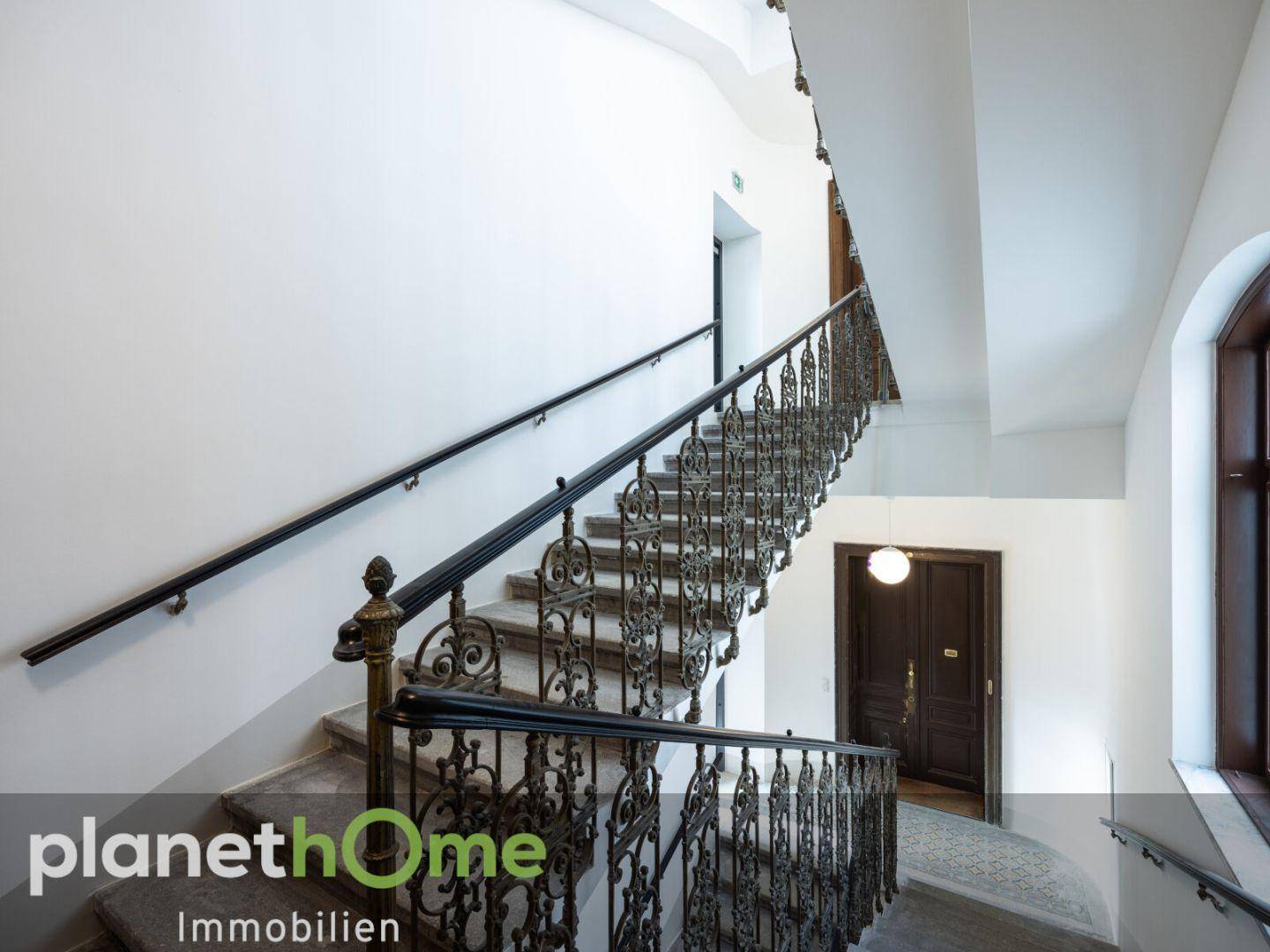 Elegantes Treppenhaus mit schmiedeeisernem Geländer und Marmorstufen in einem Altbau.