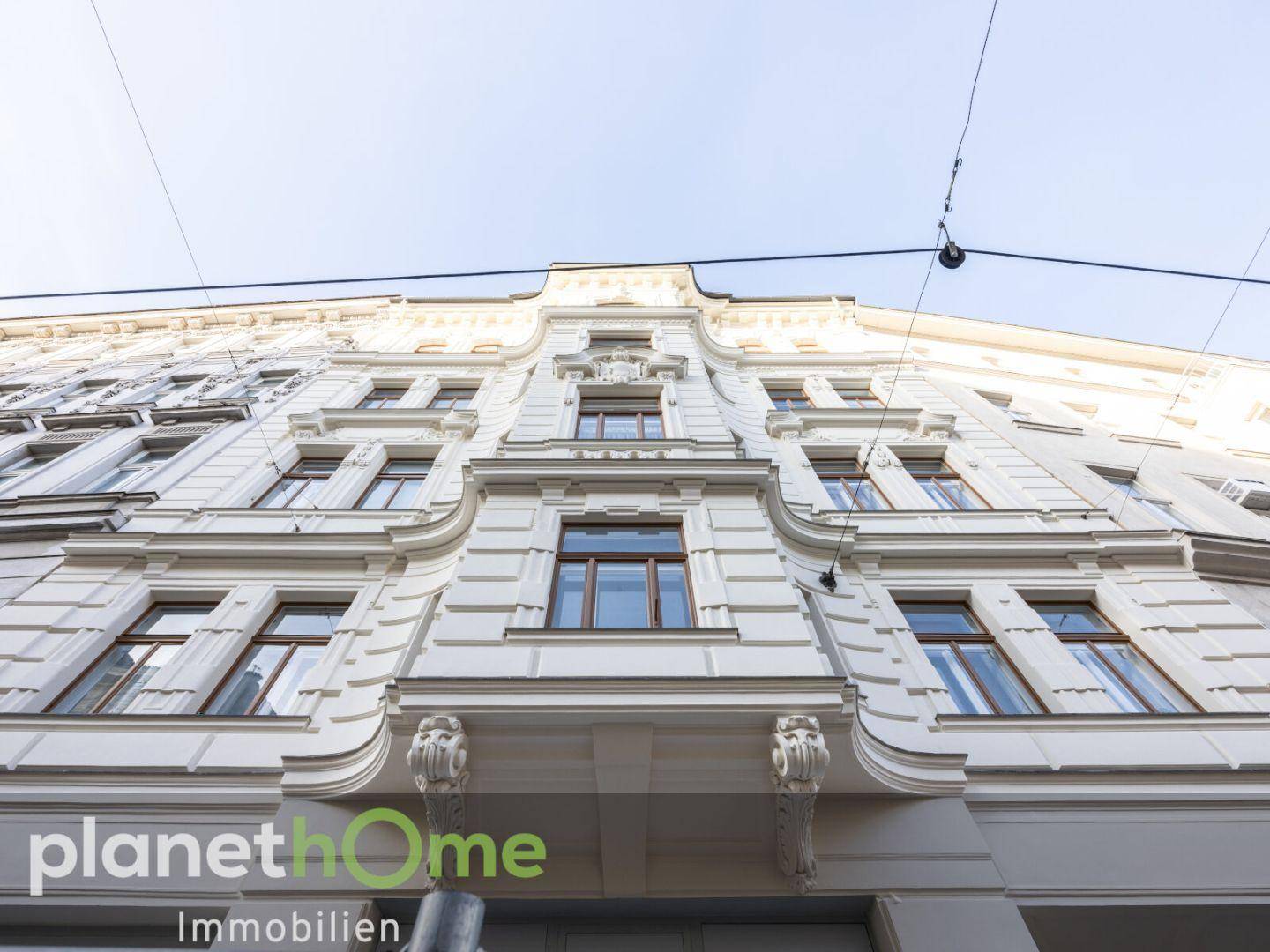 Historische Fassade eines Altbaus mit eleganten Verzierungen und klassischen Fenstern.